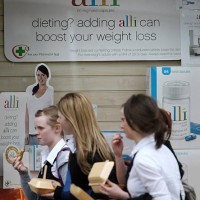 Schoolgirls eating fast food walk past a chemist stocking the Alli slimming pill on April 23, 2009 in Edinburgh, Scotland. The slimming pill, now...