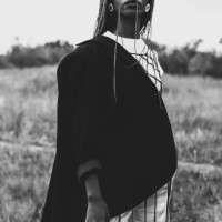 schwarz-weiß-fotografie. schöne frau in anzug und jacke im freien. authentischer stil. sommermode. model mit afro-frisur. stilvolle accessoires. ohrringe. - fashion stock-fotos und bilder