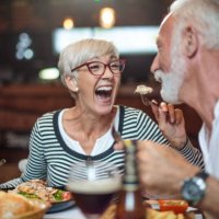 senior bei der fütterung ihrer männlichen partner im restaurant lachende frau - junk food stock-fotos und bilder