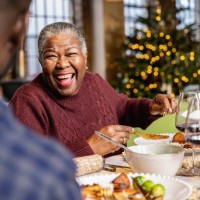 senior black woman laughing at dinner table on christmas day - home decoration stock pictures, royalty-free photos & images