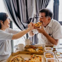 senior couple eating pizza at home - junk food stock pictures, royalty-free photos & images