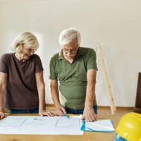 senior couple examining blueprints during home renovation process. - home decoration stock pictures, royalty-free photos & images