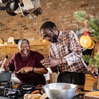 senior couple joke with each other as they cook together - food stock pictures, royalty-free photos & images