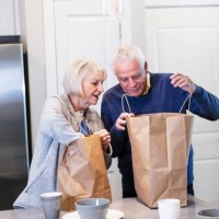 senior couple with bags of take out food in home kitchen - junk food stock pictures, royalty-free photos & images