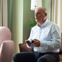 senior man enjoying video game on playstation, having fun at home - junk food stock pictures, royalty-free photos & images