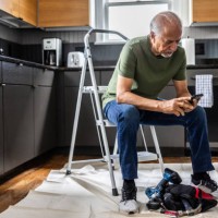 senior man man using smartphone in kitchen during a home improvement project - home decoration stock-fotos und bilder