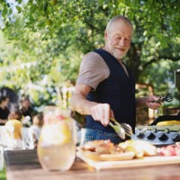 senior man on outdoor summer barbecue garden party, preparing food on grill. - garden decoration photos et images de collection