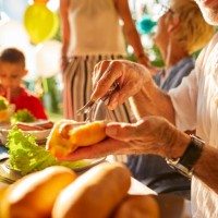 senior man preparing a hot dog on a garden party - garden decoration stock pictures, royalty-free photos & images