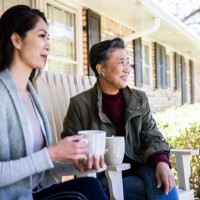 senior mother and adult daughter having coffee on front porch - garden decoration photos et images de collection