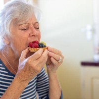 senior woman enjoying eating a fruit tart - junk food stock pictures, royalty-free photos & images
