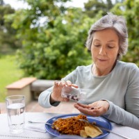 senior woman taking her medicines with food while eating lunch - food stock pictures, royalty-free photos & images
