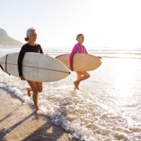senior women going for a morning surf in the sea - travel stock pictures, royalty-free photos & images