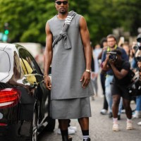 Serge Ibaka wears a black sailor's hat, black sunglasses, a gray with white striped print pattern wool pullover, a gray long / large tank-top, a...