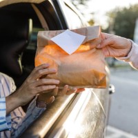 service person giving customer her order at the drive through - junk food stock pictures, royalty-free photos & images