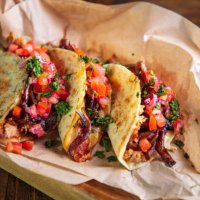 serving of tacos with shredded roast pork and cheese filling on brown paper in wooden plate - junk food stock pictures, royalty-free photos & images