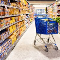 shopping cart in the aisle of a supermarket - junk food stock pictures, royalty-free photos & images