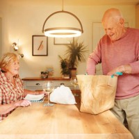 shot of a senior man unpacking takeout food from a paper bag to enjoy with his wife at home - junk food stock pictures, royalty-free photos & images