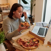 shot of a young woman enjoying some pizza while using her smartphone to make a phone call - junk food stock pictures, royalty-free photos & images