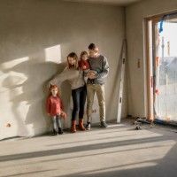 siblings with parents standing in front of wall at incomplete home - home decoration stockfoto's en -beelden