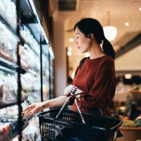 side profile of beautiful young asian woman carrying a shopping basket, grocery shopping for daily necessities in supermarket. healthy eating lifestyle. making healthier food choices - food fotografías e imágenes de stock