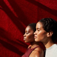 side view of women standing against red wall - fashion stock pictures, royalty-free photos & images