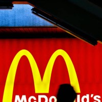 Silhouetted pedestrian lights up a cigarette as he walks past a fast food billboard for US chain McDonald's in Hong Kong, 07 March 2007. Hong Kong's...