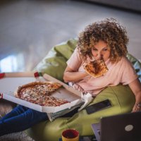 single woman watching online tv and eating pizza - junk food stock pictures, royalty-free photos & images