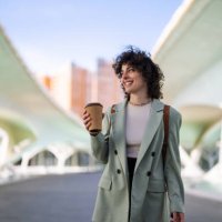 smart young female student looking away while holding coffee to go. - junk food stock pictures, royalty-free photos & images
