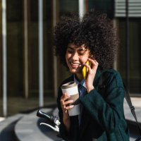 smiley woman using a mobile while drinking a take away coffee - junk food stock pictures, royalty-free photos & images
