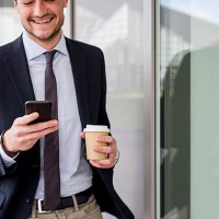 smiling businessman looking at cell phone outdoors - junk food stock pictures, royalty-free photos & images