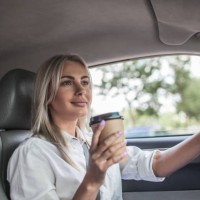 smiling businesswoman holding takeaway coffee driving car - junk food stock pictures, royalty-free photos & images