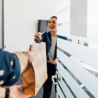 smiling businesswoman taking food delivery in office - junk food stock pictures, royalty-free photos & images