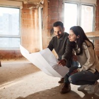 smiling couple analyzing plans at their renovating apartment. - home decoration stock pictures, royalty-free photos & images