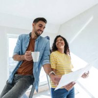 smiling couple having discussion over blueprint for renovation in new home - home decoration stockfoto's en -beelden