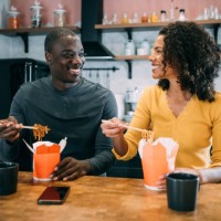 smiling couple having lunch together at home. - junk food stock pictures, royalty-free photos & images