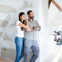 smiling couple in attic to be renovated looking out of window - home decoration stock pictures, royalty-free photos & images