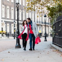smiling couple walking along the street with shopping bags - fashion stock pictures, royalty-free photos & images