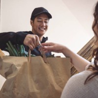 smiling delivery man delivering vegetables to customer while talking at doorstep - food stock pictures, royalty-free photos & images