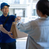 smiling delivery man delivers food to a woman standing at the door. - food stock pictures, royalty-free photos & images