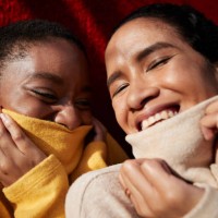 smiling female friends against red wall - fashion stock pictures, royalty-free photos & images