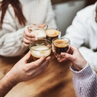 smiling friends making celebratory toast at home with different types of coffee - coffee stockfoto's en -beelden