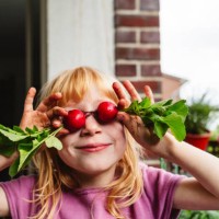 smiling girl covering eyes with fresh radish on balcony - food stock pictures, royalty-free photos & images