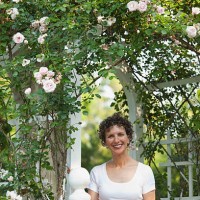smiling hispanic woman standing underneath trellis - garden decoration stock-fotos und bilder