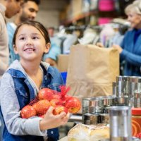 smiling little girl donates apples to food bank - food stock pictures, royalty-free photos & images