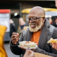 smiling londoner enjoying convenience food outdoors - junk food stock pictures, royalty-free photos & images
