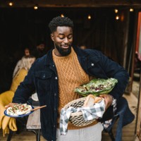 smiling man balancing food while standing at doorway during social gathering - food photos et images de collection