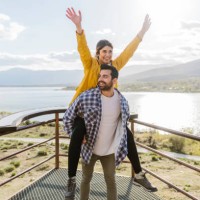smiling man giving piggyback ride to girlfriend at observation point - travel photos et images de collection