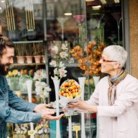 smiling man taking a flower bouquet from a senior florist - garden decoration stock pictures, royalty-free photos & images