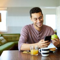 smiling man using mobile phone while holding apple - food stock pictures, royalty-free photos & images