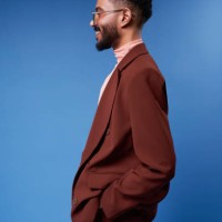 smiling man wearing brown blazer standing against blue background - fashion stock pictures, royalty-free photos & images